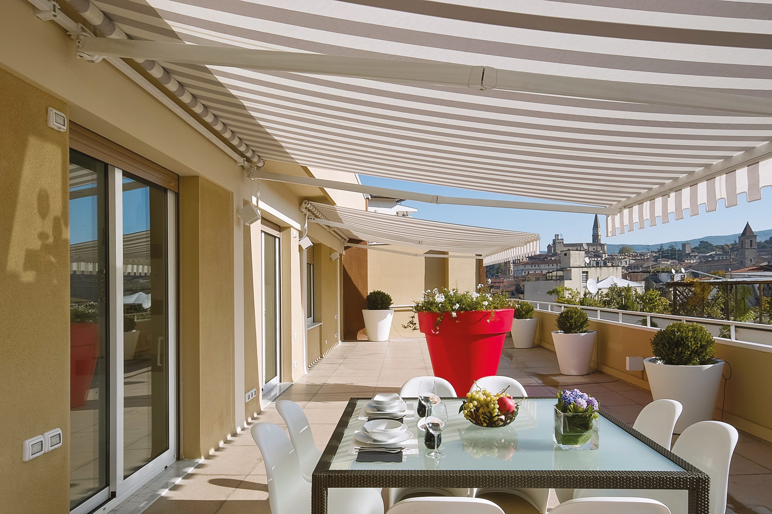 Store banne rayé beige et blanc faisant de l'ombre sur la grande terrasse surélevée