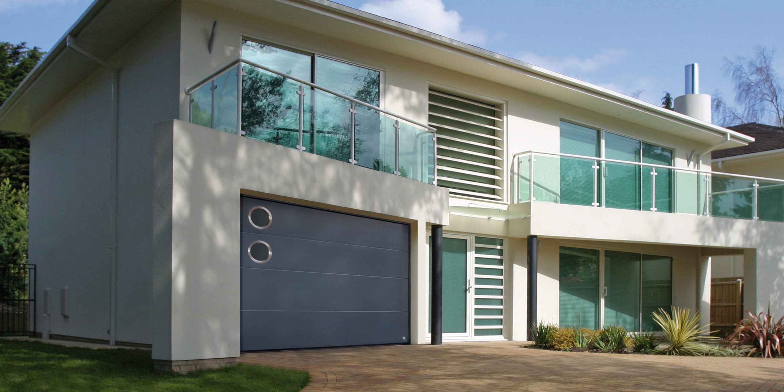 Belle maison luxueuse avec une porte de garage grise comprenant deux hublots